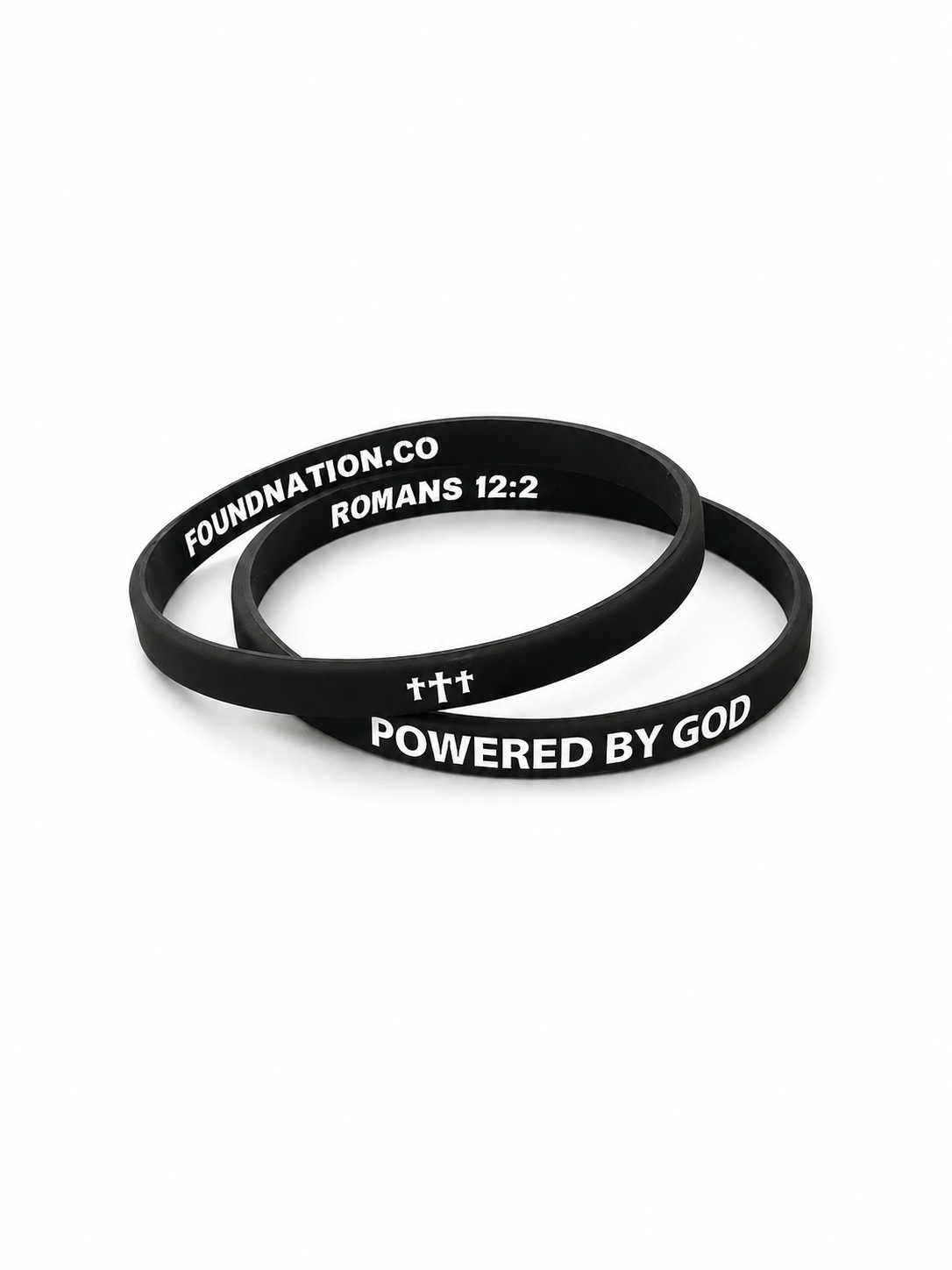 Two black silicone wristbands with white printed text 'POWERED BY GOD' and triple crosses, with FOUNDATION.CO and ROMANS 12:2 on inside, shown on a white background.